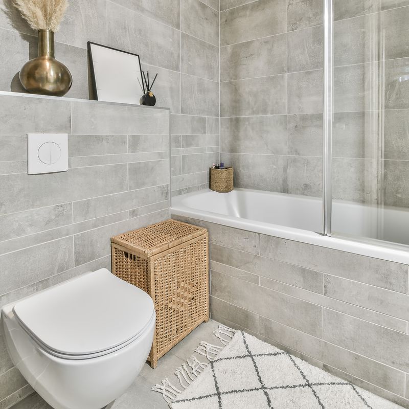 Finished bathroom with a tiled tub surround, glass shower screen and warm neutral finishes