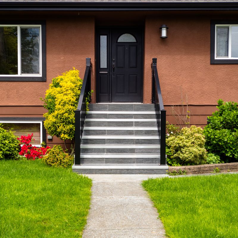 Finished stucco facade with tiled front steps, railings and an entry door