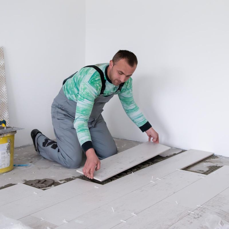 Installer laying wood-look floor tiles in a residential room